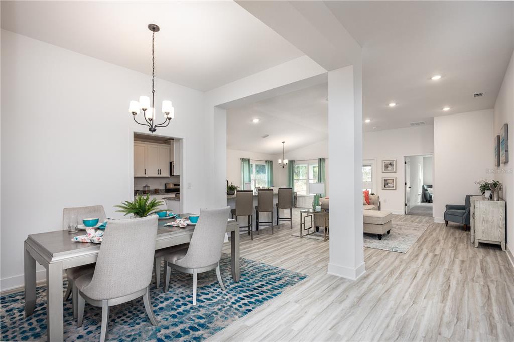 A dining area with a patterned rug opens into a kitchen and living space — 13651 NW 150TH CIRCLE, ALACHUA, FL
