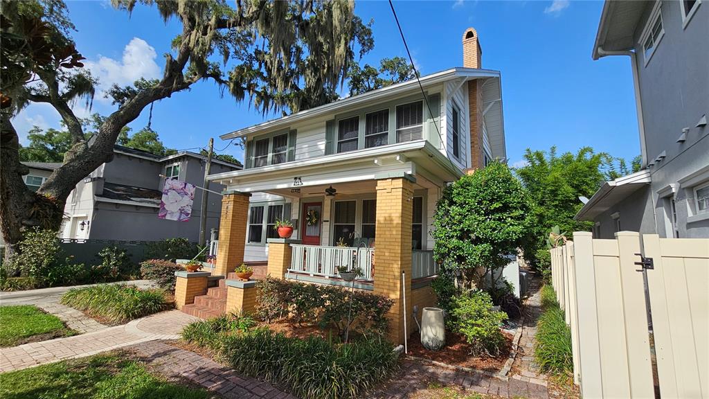A two-story house with a brick-columned front porch and a large oak tree — 821 N EOLA DRIVE, ORLANDO, FL