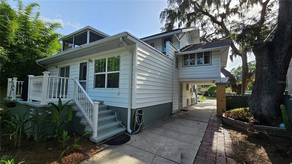 The exterior of a white two-story house features a wooden deck, stairs, and a driveway — 821 N EOLA DRIVE, ORLANDO, FL