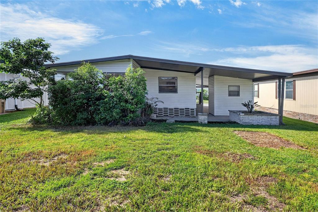 A single-story manufactured home features a large carport, white siding, and a landscaped front yard — 2055 S FLORAL AVENUE UNIT 55, BARTOW, FL