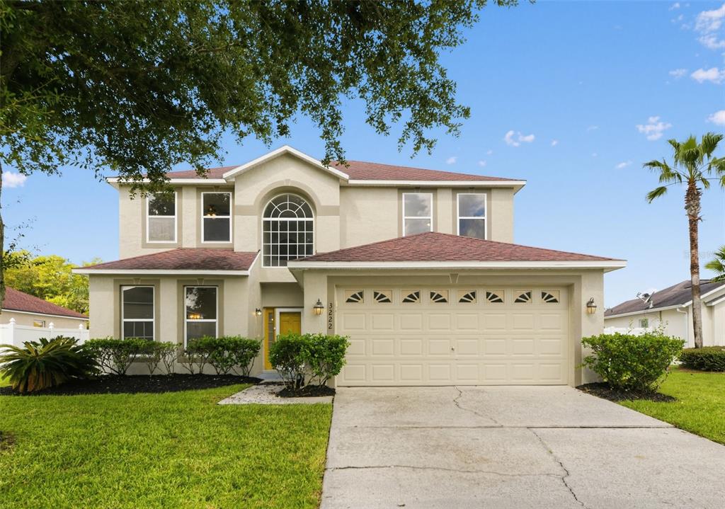 A two-story suburban house with a beige stucco exterior, a two-car garage, and a driveway — 3222 RESERVE COURT, ORLANDO, FL