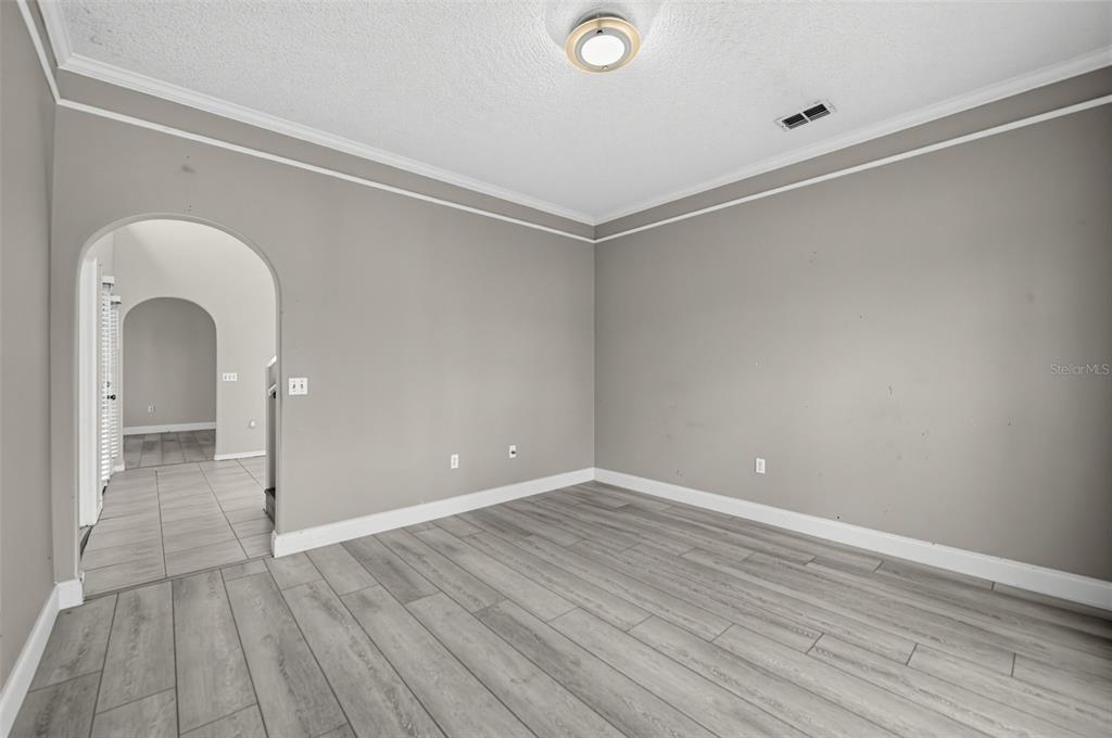 An empty room with gray walls, light wood-look flooring, and an arched doorway — 3222 RESERVE COURT, ORLANDO, FL