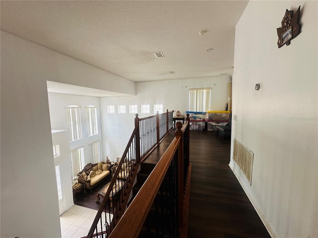 An elevated view of a staircase landing overlooking a living room with high ceilings — 2530 SAND ARBOR CIRCLE, ORLANDO, FL