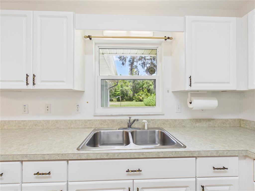 A kitchen sink with a double basin sits below a window overlooking a grassy yard — 11236 N RAIN POINT, INGLIS, FL