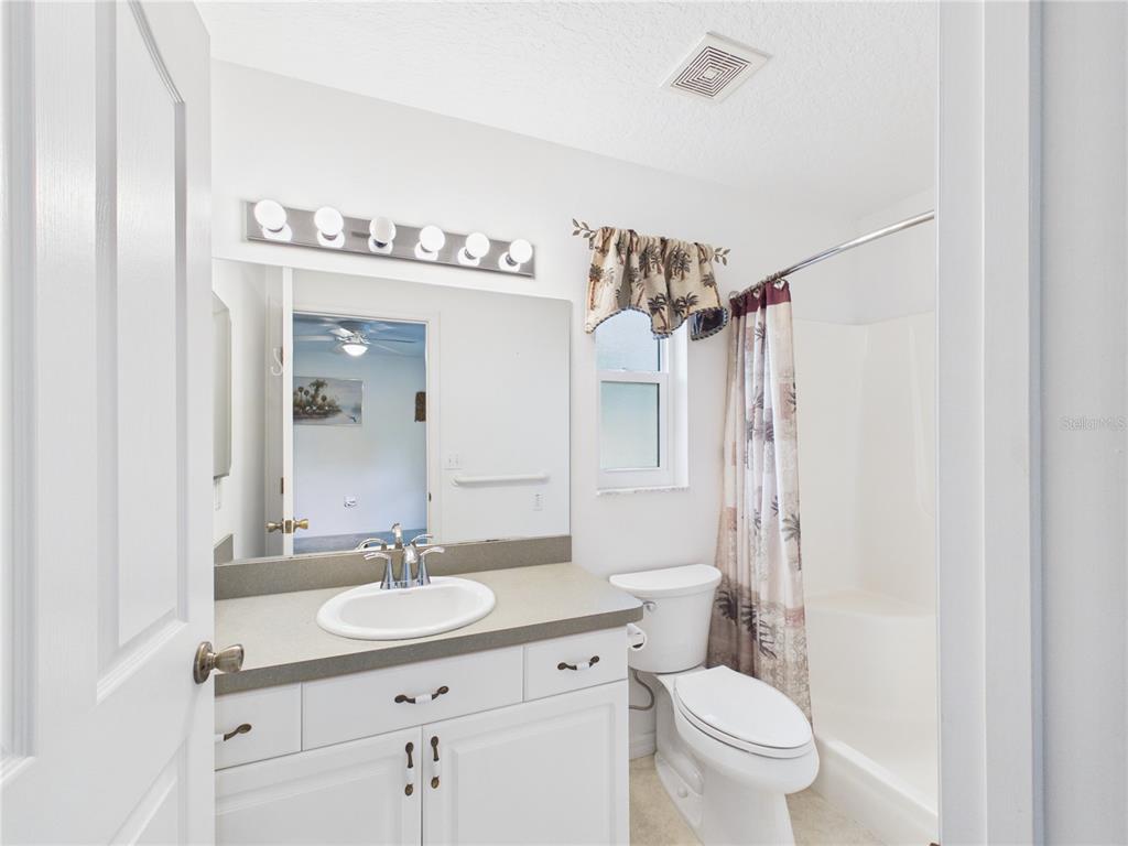 A bathroom features a white vanity, a mirror, a toilet, and a shower-tub combination — 11236 N RAIN POINT, INGLIS, FL
