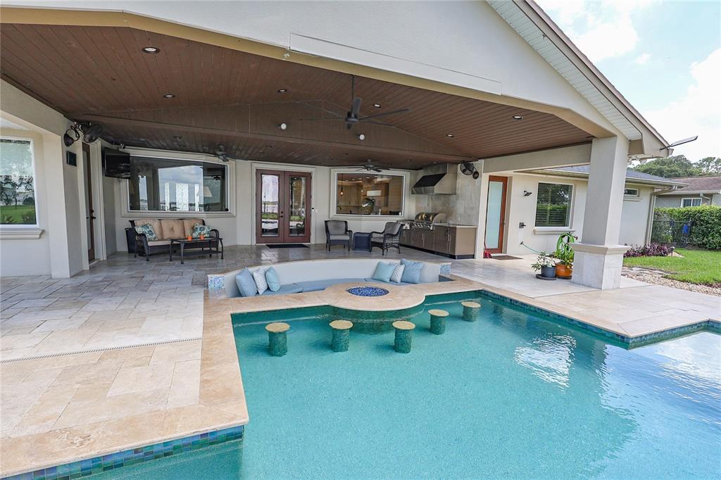 A covered patio features a sunken seating area with a fire pit and swim-up bar — 3640 CRUMP ROAD, WINTER HAVEN, FL