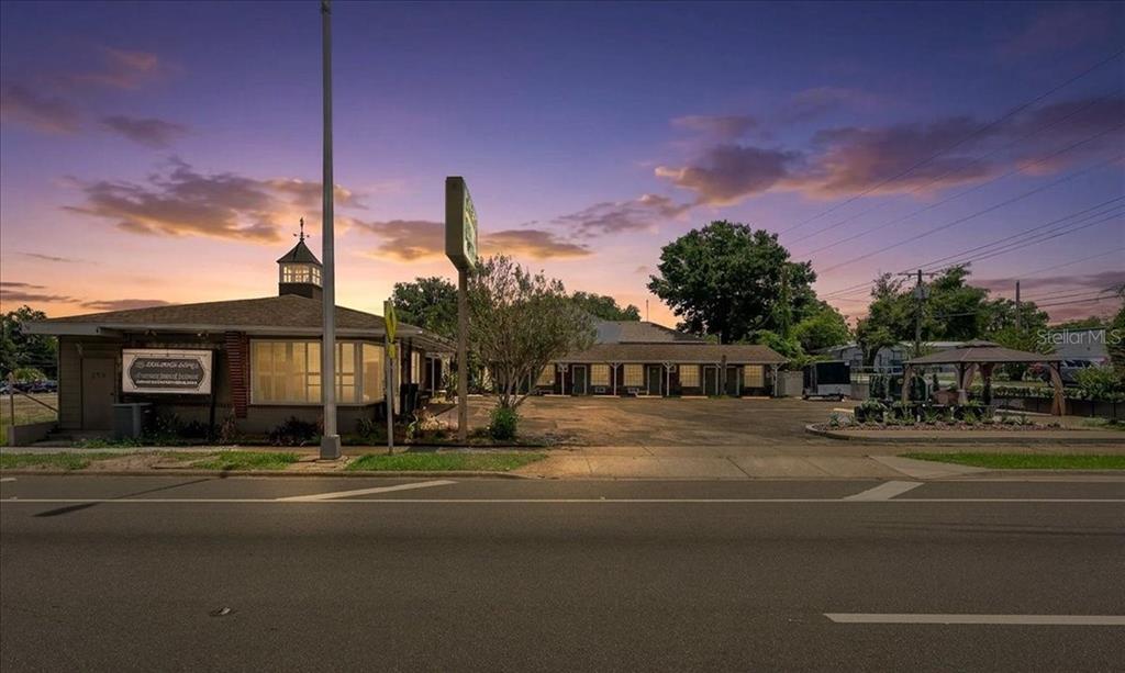 A roadside motel with a parking lot and a cupola sits under a sunset sky — 215 S PINE AVENUE, OCALA, FL