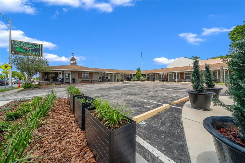 A low-rise motel building with a parking lot and decorative planters in the foreground — 215 S PINE AVENUE, OCALA, FL