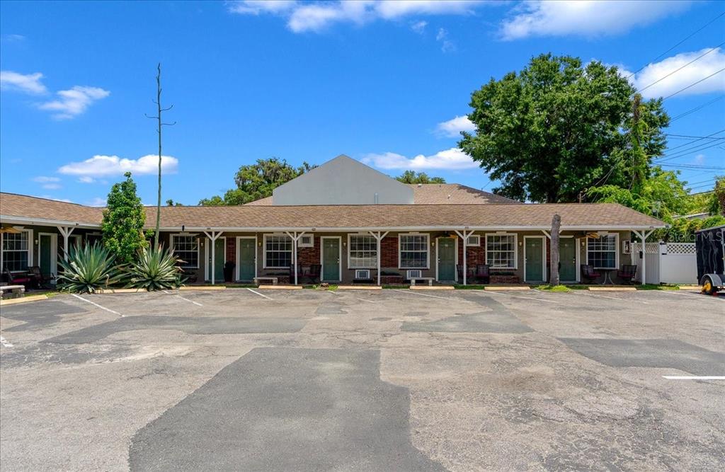 A single-story motel building with a parking lot in the foreground under a blue sky — 215 S PINE AVENUE, OCALA, FL