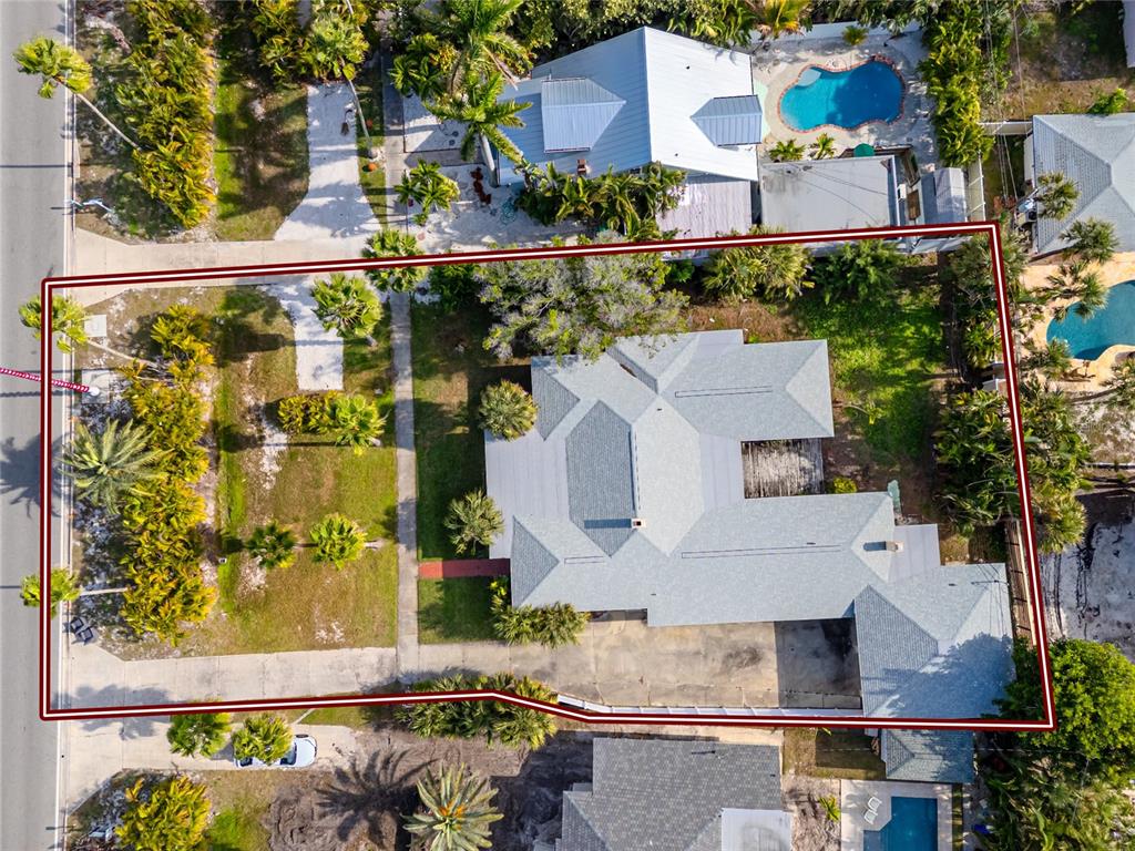 An aerial view shows a house with a gray roof surrounded by palm trees — 3312 E MARITANA DRIVE, ST PETE BEACH, FL