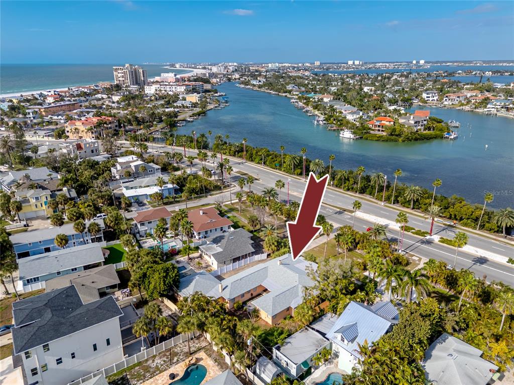 An aerial view shows a residential property with a light-colored roof near a coastal waterway — 3312 E MARITANA DRIVE, ST PETE BEACH, FL