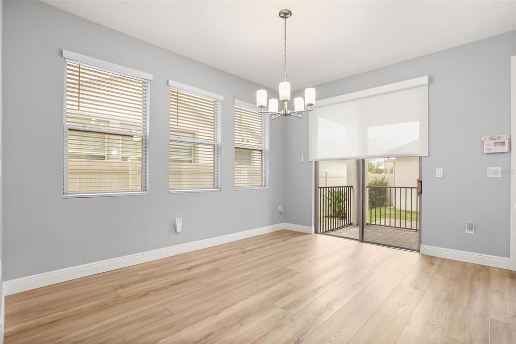 A dining area with light wood flooring, gray walls, a chandelier, and sliding glass doors — 154 WOODED VINE DRIVE, WINTER SPRINGS, FL