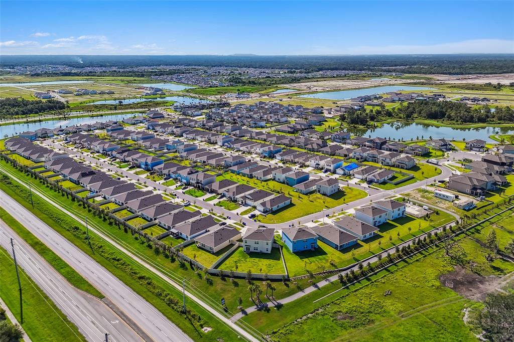 An aerial view shows a suburban neighborhood with many houses, ponds, and a nearby road — 5615 FREESIA DRIVE, LAKELAND, FL