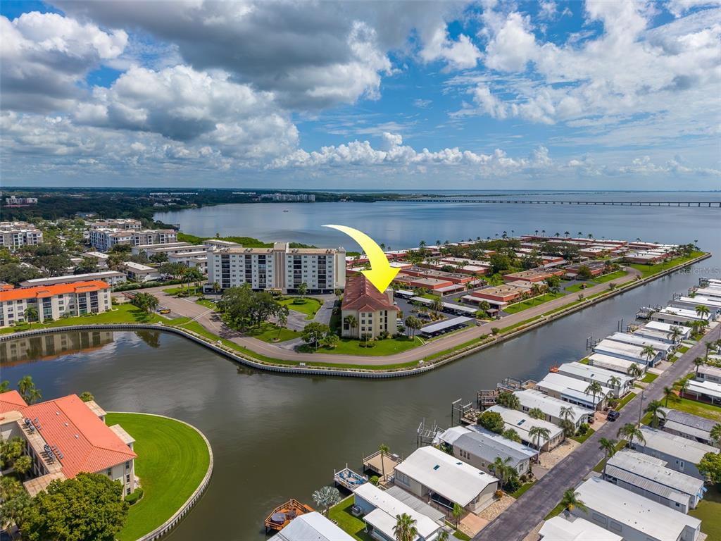 An aerial view shows a multi-story apartment building surrounded by a canal and residential homes — 19029 US HIGHWAY 19 N UNIT 26-204, CLEARWATER, FL