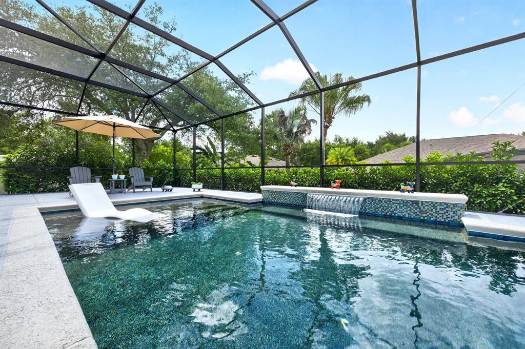 A swimming pool with a water feature and a lounge chair inside a screened enclosure — 2651 CEDAR CREST DRIVE, APOPKA, FL