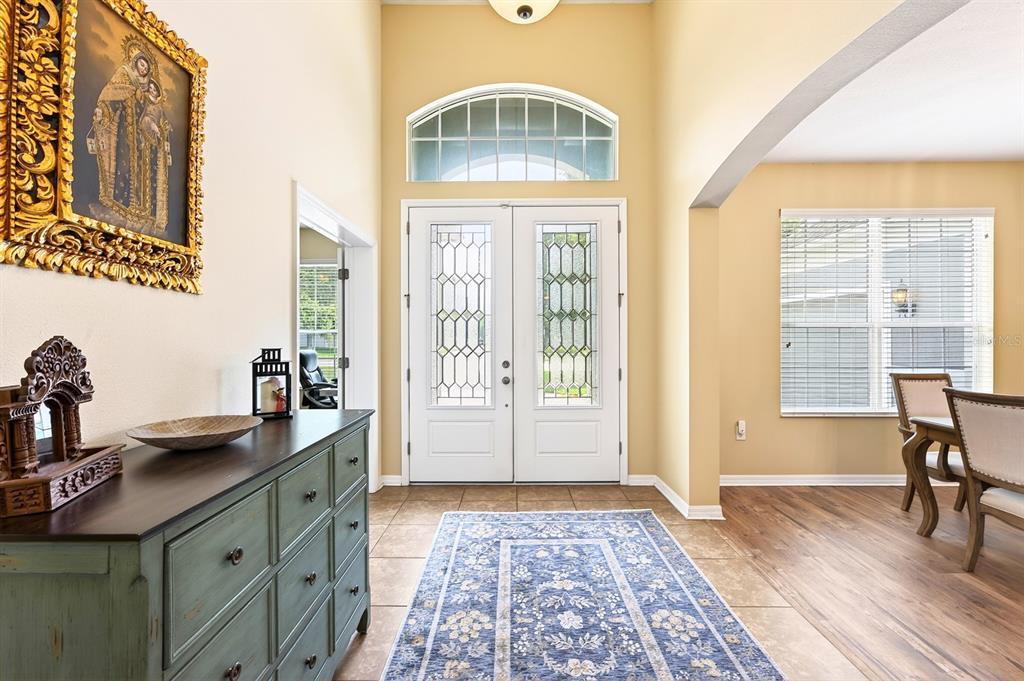 A foyer features a blue runner rug, a green dresser, and double glass-paneled entry doors — 2651 CEDAR CREST DRIVE, APOPKA, FL
