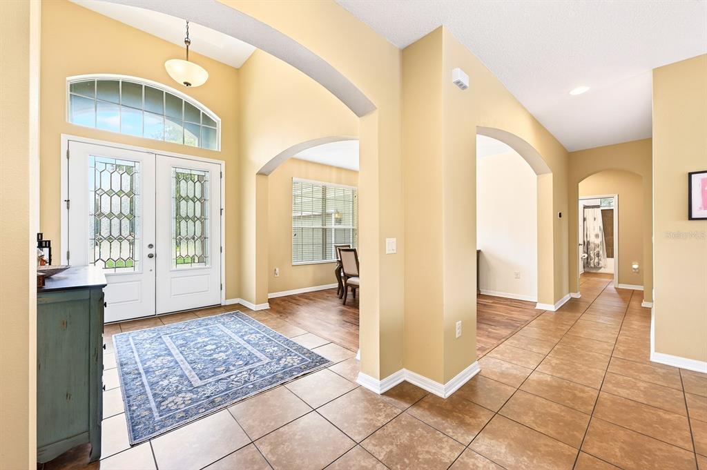 An entryway with tile flooring, arched doorways, a blue area rug, and double front doors — 2651 CEDAR CREST DRIVE, APOPKA, FL