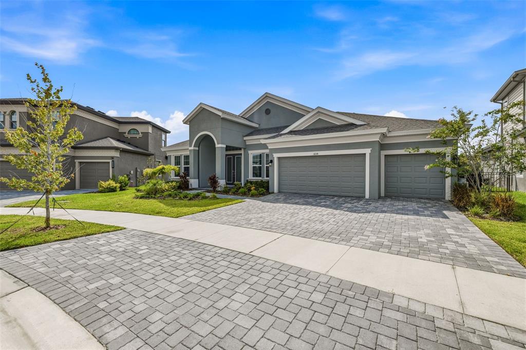 A gray single-story house with a paver driveway and a three-car garage — 5254 WOLF CREEK DRIVE, APOLLO BEACH, FL
