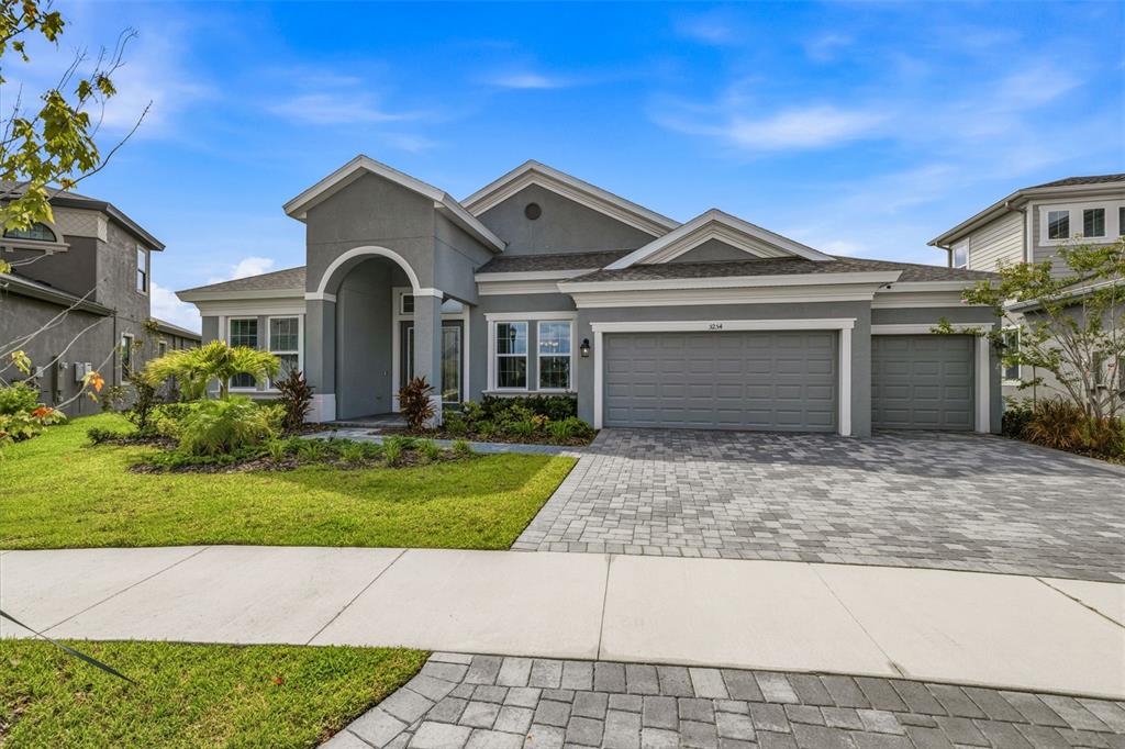 A gray single-story house with a paved driveway, three-car garage, and a covered entryway — 5254 WOLF CREEK DRIVE, APOLLO BEACH, FL