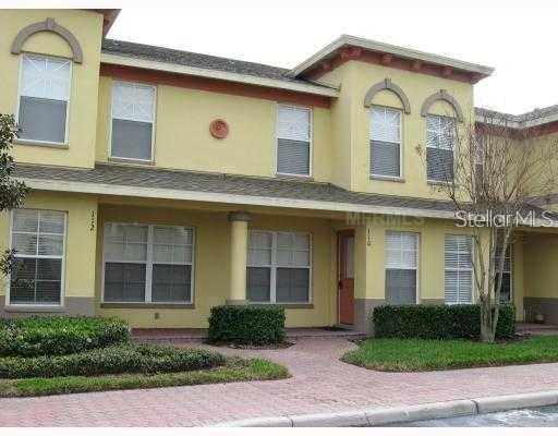 A two-story yellow townhouse with a covered entryway and a brick-paved walkway — 110 COQUINA BAY DRIVE, ST PETERSBURG, FL