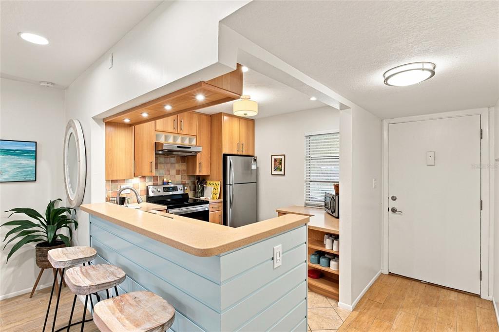 A kitchen with light wood cabinets, a breakfast bar, and a white front door — 3868 CATALINA DRIVE, BRADENTON, FL