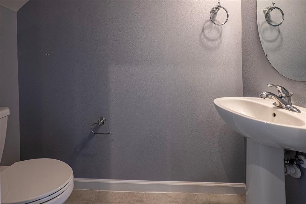 A bathroom features a pedestal sink, a toilet, and a wall-mounted toilet paper holder — 3084 INLET BREEZE WAY, HOLIDAY, FL