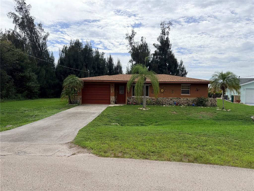 A single-story house with a brown exterior, stone facade, and a concrete driveway — 601 INDIAN CREEK LANE, PUNTA GORDA, FL