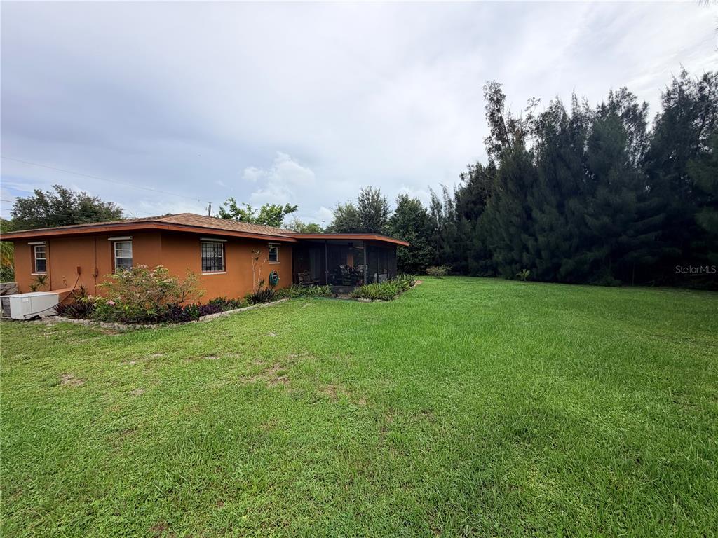 A single-story orange house with a screened-in porch sits beside a large grassy yard — 601 INDIAN CREEK LANE, PUNTA GORDA, FL