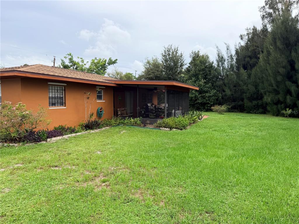 The exterior of a house with orange stucco walls and a screened-in back porch — 601 INDIAN CREEK LANE, PUNTA GORDA, FL
