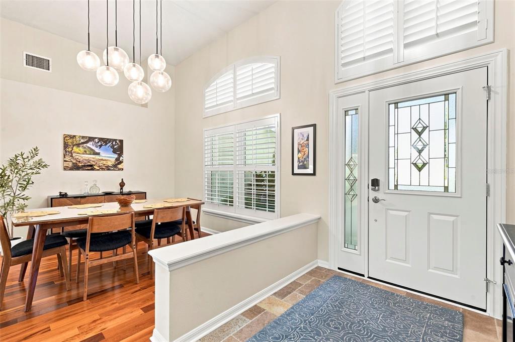 A dining area with wood floors and a pendant light fixture sits beside an entryway — 17322 HUBERS COURT, ODESSA, FL