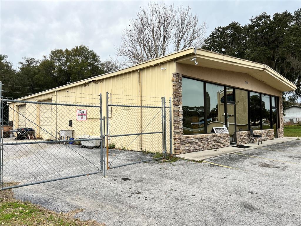 A single-story commercial building with a metal exterior, stone facade, and a chain-link fenced lot — 2018 N FLORIDA AVENUE, HERNANDO, FL