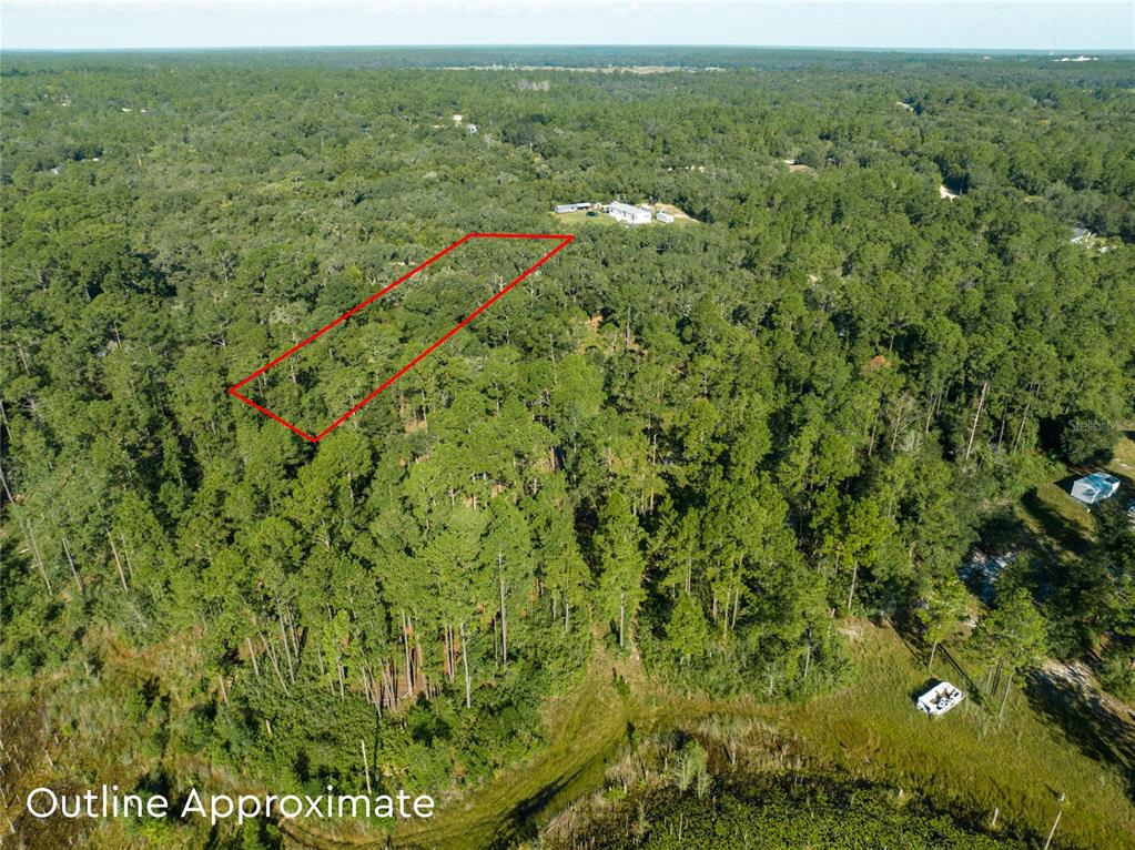An aerial view shows a rectangular plot of land outlined in red amidst dense forest — 5790 BRYCE STREET, KEYSTONE HEIGHTS, FL