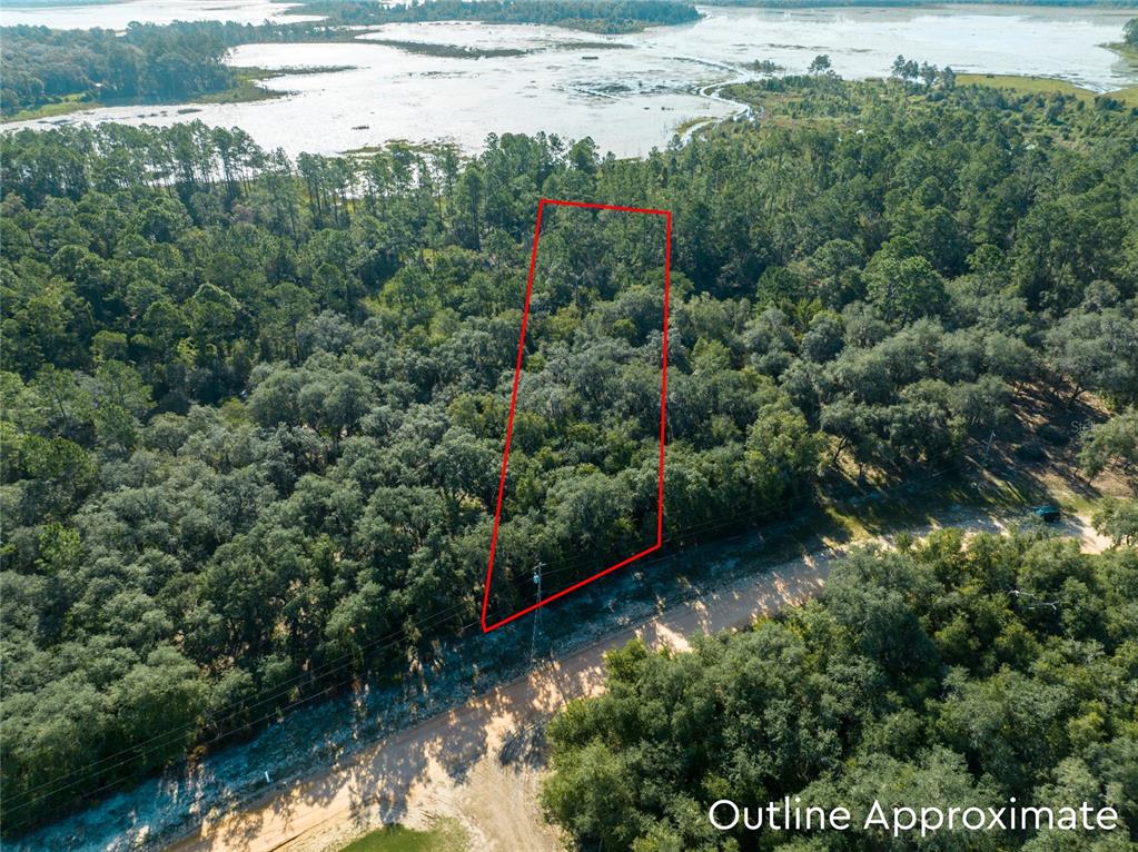 An aerial view shows a wooded lot outlined in red next to a dirt road — 5790 BRYCE STREET, KEYSTONE HEIGHTS, FL
