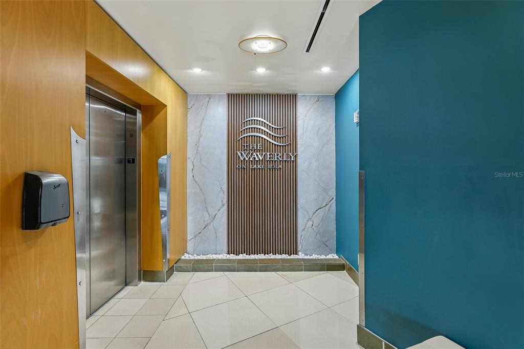 An elevator lobby features wood-paneled walls, a marble accent wall with signage, and tile flooring — 322 E CENTRAL BOULEVARD UNIT 806, ORLANDO, FL
