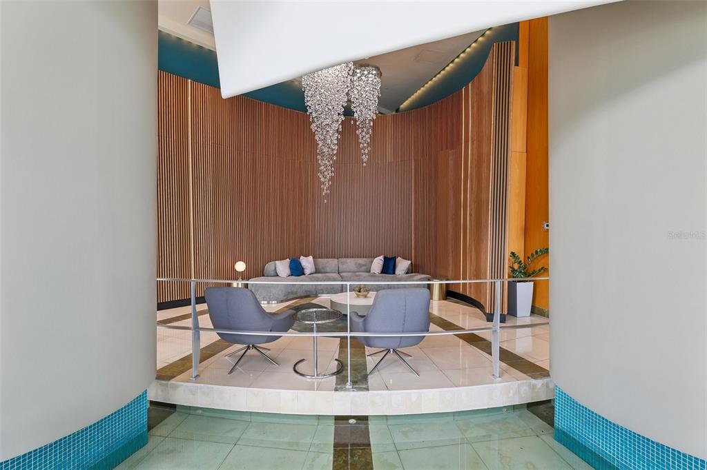 A modern lounge area features a curved wood-slat wall, a crystal chandelier, and gray seating — 322 E CENTRAL BOULEVARD UNIT 806, ORLANDO, FL