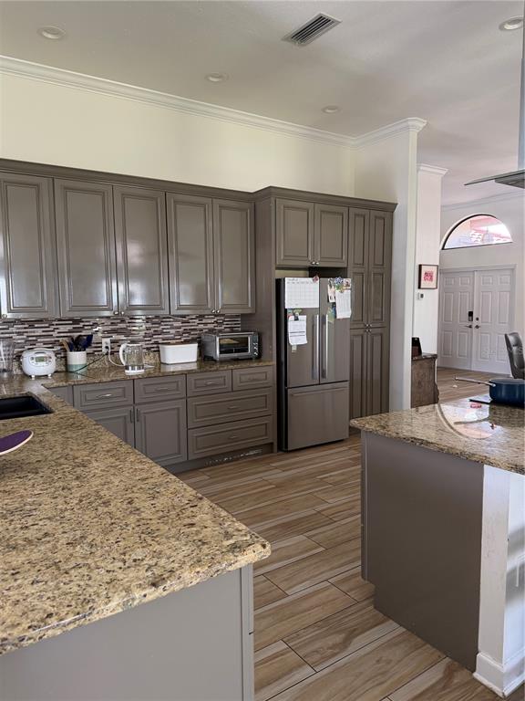 A kitchen features gray cabinets, granite countertops, a stainless steel refrigerator, and wood-look tile flooring — 4931 FALLCREST CIRCLE, SARASOTA, FL