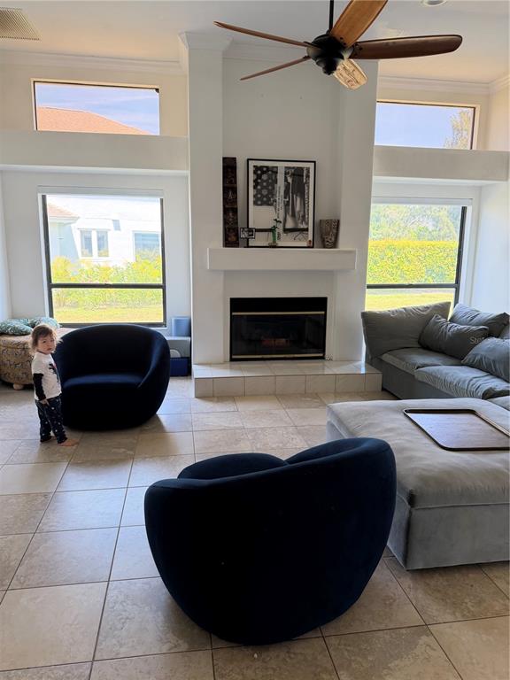 A living room features a fireplace, two dark rounded chairs, a gray sectional, and tile flooring — 4931 FALLCREST CIRCLE, SARASOTA, FL