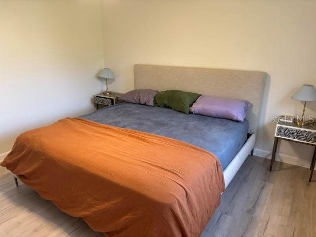 A bedroom features a bed with an orange throw, a beige headboard, and two nightstands — 4931 FALLCREST CIRCLE, SARASOTA, FL