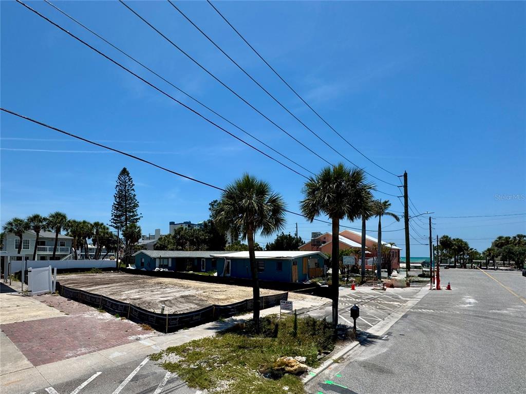 A vacant lot with a black silt fence sits next to a small blue building — 630 COREY AVENUE, ST PETE BEACH, FL
