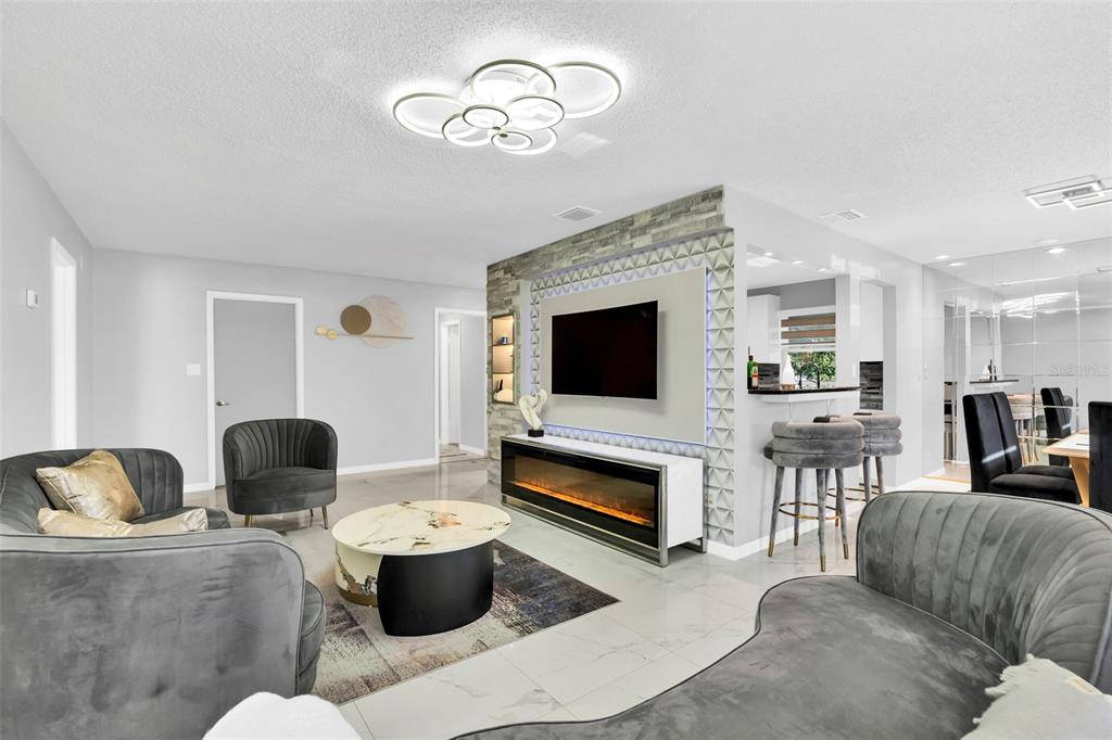 A living room features a stone accent wall with a television and electric fireplace — 5316 JADE STREET, KISSIMMEE, FL