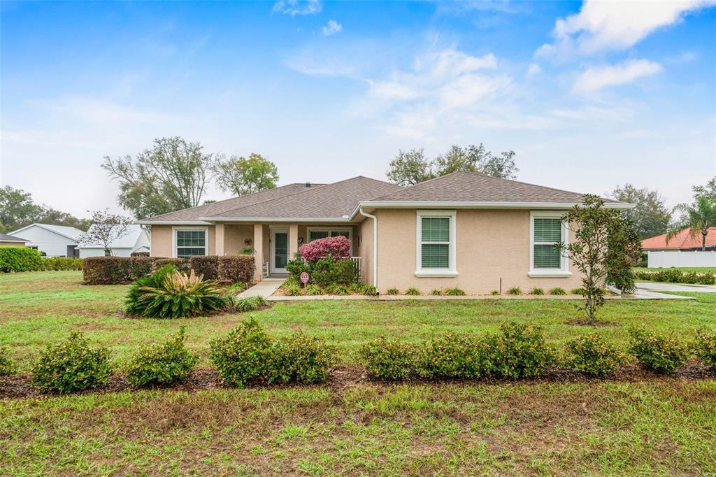 A single-story tan house with a hip roof and a front lawn with landscaping — 276 N CUNNINGHAM AVENUE, INVERNESS, FL