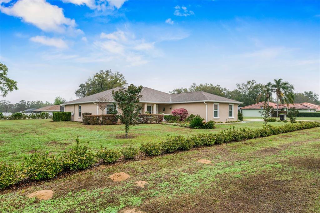 A single-story tan house with a hip roof sits on a large grassy lot — 276 N CUNNINGHAM AVENUE, INVERNESS, FL