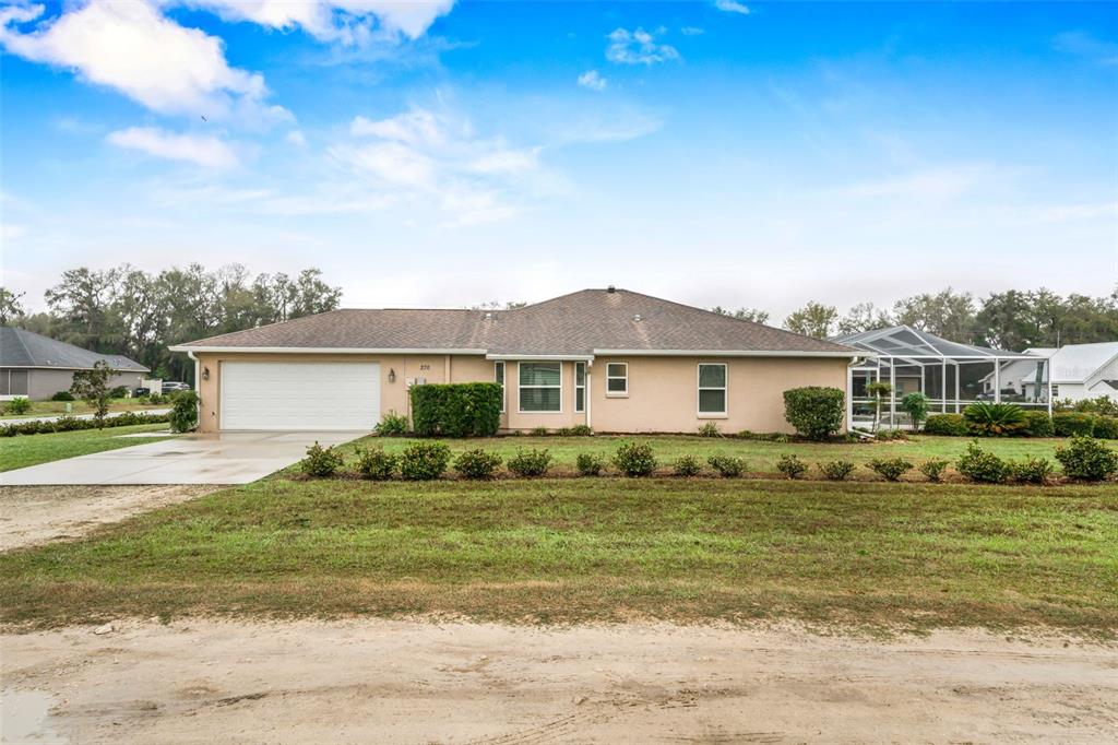 A single-story house with a tan exterior, a two-car garage, and a screened-in back porch — 276 N CUNNINGHAM AVENUE, INVERNESS, FL