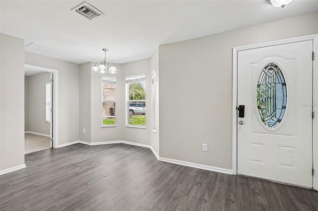 An empty bedroom with beige carpet, light gray walls, a window, and a white closet — 449 DANUBE DRIVE, KISSIMMEE, FL
