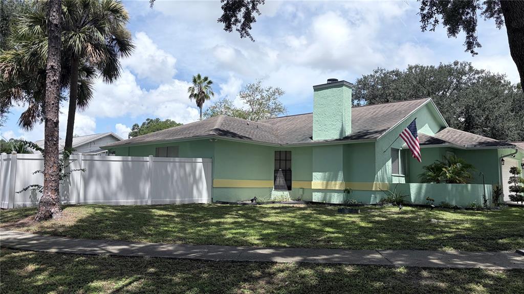 A light green single-story house with a chimney and a white privacy fence — 4142 YELLOWWOOD DRIVE, VALRICO, FL