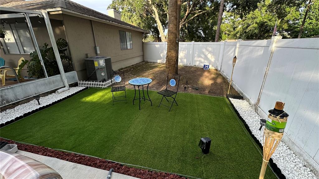 A small backyard features artificial turf, a bistro set, and a white vinyl privacy fence — 4142 YELLOWWOOD DRIVE, VALRICO, FL