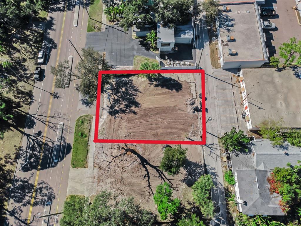 An aerial view shows a cleared, vacant lot bordered by a street and mature trees — 7309 1ST AVENUE S, ST PETERSBURG, FL