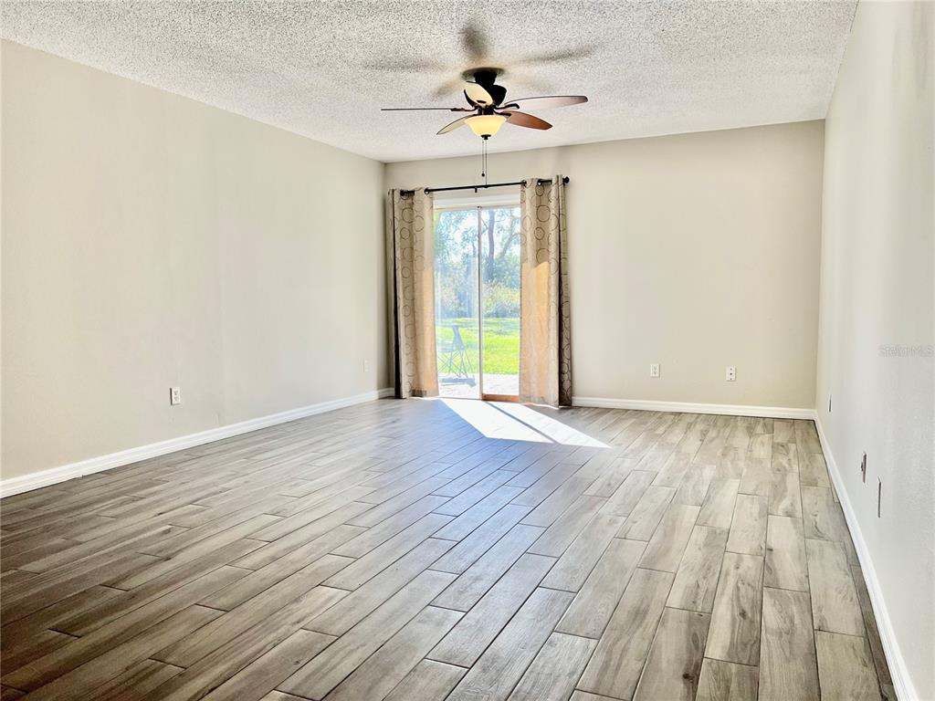An empty room with wood-look tile flooring, a ceiling fan, and sliding glass patio doors — 1820 CENTRAL PARK AVENUE, ORLANDO, FL