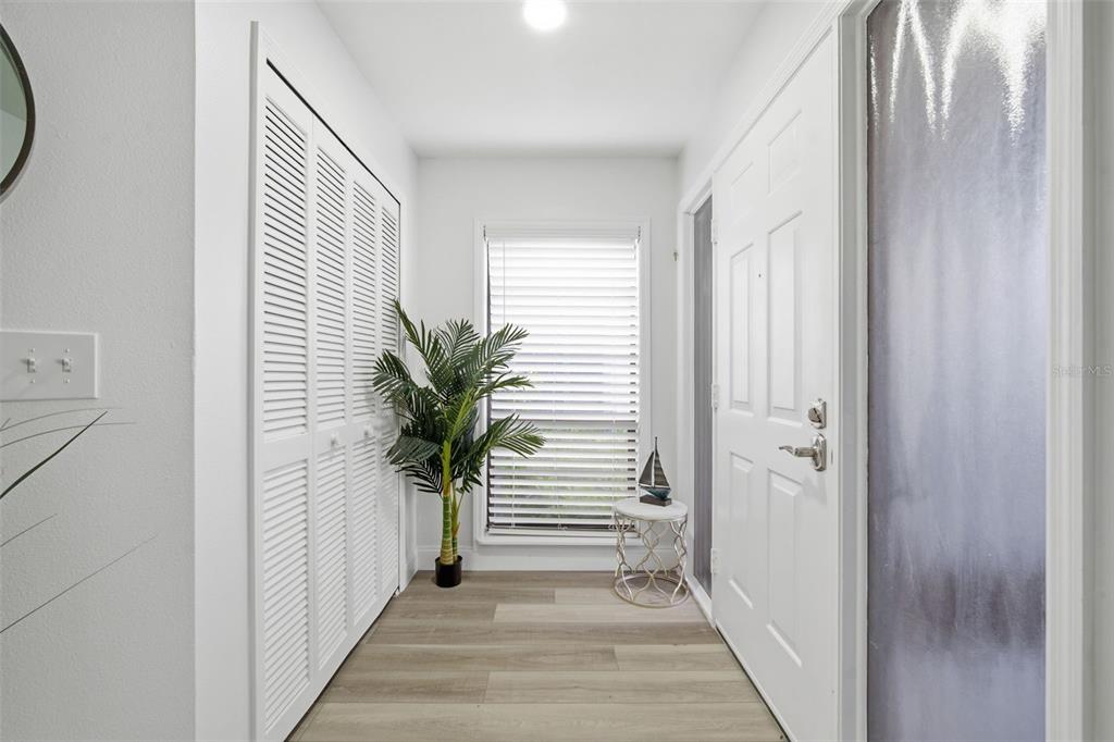 A bright entryway features white louvered closet doors, a window with blinds, and wood-look flooring — 9100 PARK BOULEVARD UNIT 1, SEMINOLE, FL