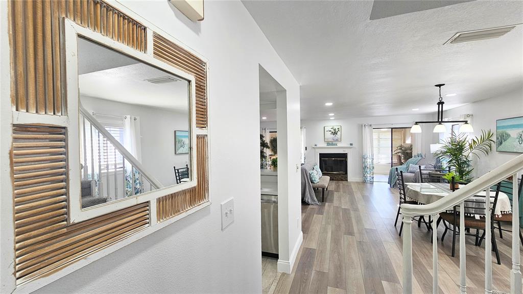 A view from a hallway looking into a living room with wood-look flooring and furniture — 9100 PARK BOULEVARD UNIT 1, SEMINOLE, FL